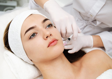 Woman getting cosmetic. injection. Beauty injections and cosmetology. Young woman in beauty salon sloseup. Plastic surgery and beauty treatment.の写真素材