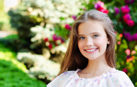 Portrait of adorable smiling little girl child in summer day. Happy preteen in the park outdoorsの写真素材
