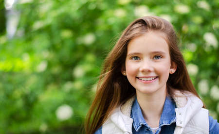 Portrait of adorable smiling little girl child pre teen in the park outdoorsの写真素材
