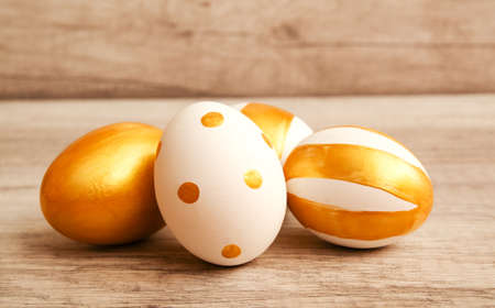 Colorful golden bright handmade painted easter eggs isolated on a wood backgroundの写真素材