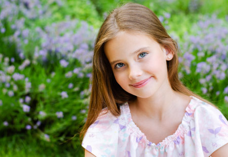 Portrait of adorable smiling little girl child in summer day. Happy preteen in the park outdoorsの写真素材