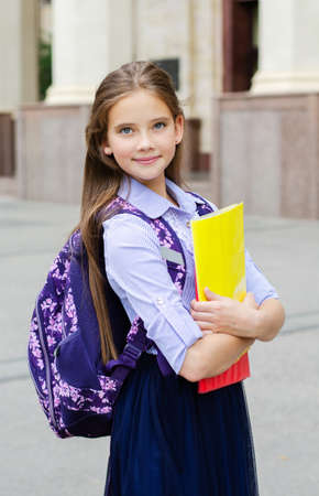 Back to school. Education concept. Cute smiling schoolgirl preteen on the way to the school. Happy little girl child holding the books with backpackの写真素材