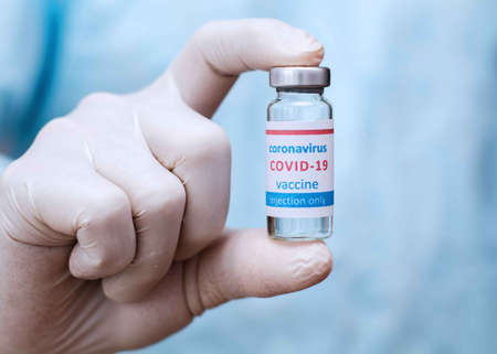 Doctor or laborant in protective gloves holding ampule tube with nCoV Coronavirus vaccineの写真素材