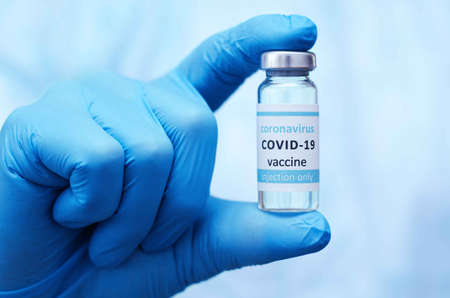 Doctor or laborant in protective gloves holding ampule tube with nCoV Coronavirus vaccine for COVID...