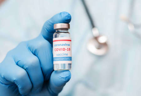 Doctor or laborant in protective gloves holding ampule tube with nCoV Coronavirus vaccineの写真素材