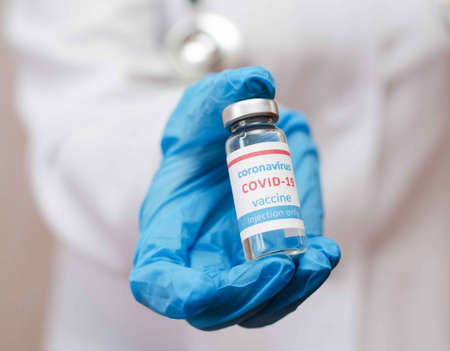 Doctor or laborant in protective gloves holding ampule tube with nCoV Coronavirus vaccineの写真素材