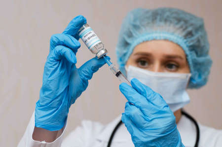 Doctor, nurse, scientist hand in blue gloves holding coronavirus, covid-19 vaccine and syring. Medicine and coronavirus concept.の写真素材