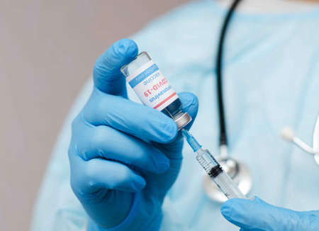 Doctor, nurse, scientist hand in blue gloves holding coronavirus, covid-19 vaccine and syring.の写真素材