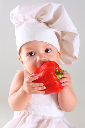 Little funny baby in a cap chef with Pepperの写真素材