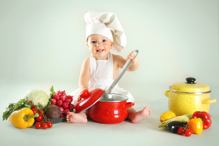 Baby wearing a chef hat with vegetables and pan  Use it for child, healthy food conceptの写真素材