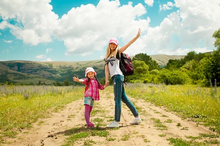 Mother and daughter walk on rural road through green field in summer  Happiness, lifestyle concept の写真素材