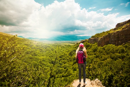 Young woman with backpack standing on cliff edge  Landscape composition  Happiness, lifestyle concept の写真素材