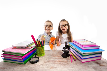 Two smiling little kids at the table children doing homework, isolated on white background  School, education concept の写真素材