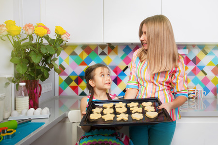 Little girl with her mother preparing a cookie on kitchen. Family, children cooking concept