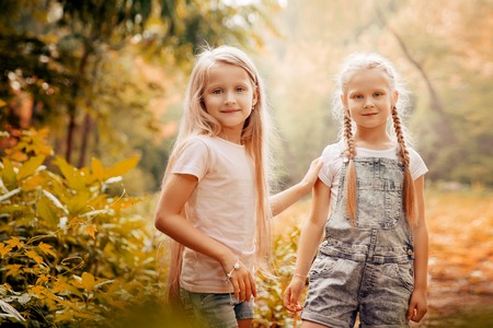 Childhood, family, friendship and people concept - two happy kids sisters hugging outdoors.の写真素材