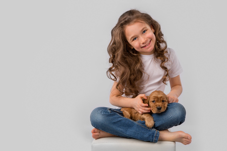 Kids pet friendship concept - little girl with red puppy isolated on white backgroundの写真素材