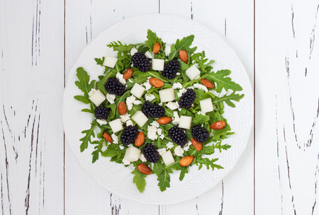 Summer green salad with arugula, melon, blackberries, almonds and feta cheeseの写真素材