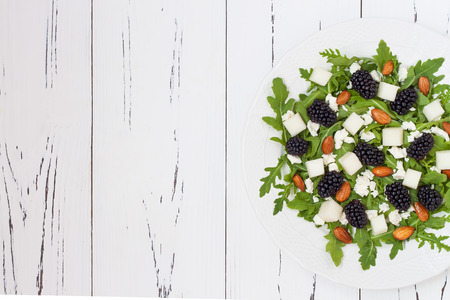 Summer green salad with arugula, melon, blackberries, almonds and feta cheese. Copy space backgroundの写真素材