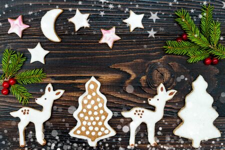 Christmas holiday background with gingerbread cookies and fir branches on the old wooden board. Drawn snowfall. Tonedの写真素材