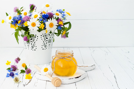 Honey and wild flowers on rustic old wooden backgroundの写真素材