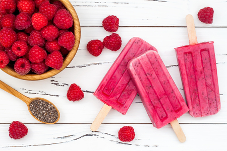 Homemade vegan raspberry coconut milk popsicles - ice pops - paletas with chia seeds on rustic white wooden backgroundの写真素材