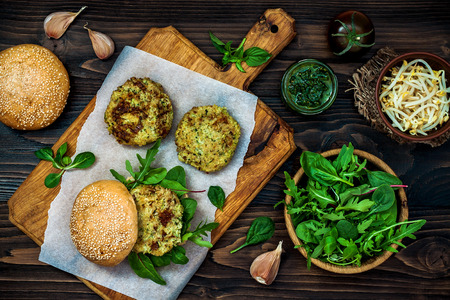 Zucchini quinoa veggie burger with pesto sauce and sprouts. Vegetarian burger on a cooking sheet ready to prepare hamburger. Top view, overhead, flat layの写真素材