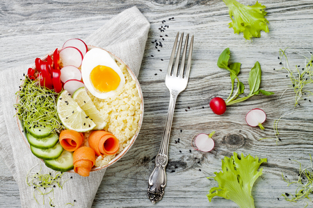 Veggies detox Buddha bowl recipe with egg, carrots, sprouts, couscous, cucumber, radishes and seeds. Top view, flat lay, copy spaceの写真素材