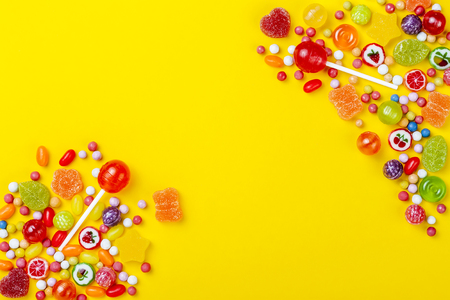 Different types of candies on yellow background, copy spaceの写真素材