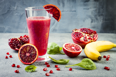 Detox fresh juice or smoothie in glass with blood oranges, greens, pomegranate. Homemade refreshing fruit beverageの写真素材