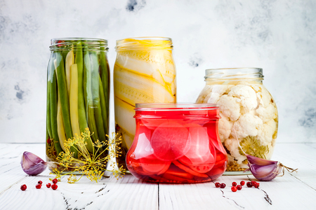 Marinated pickles variety preserving jars. Homemade green beans, squash, radish, cauliflower pickles. Fermented food.の写真素材