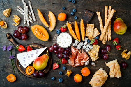 Appetizers table with italian antipasti snacks. Cheese and charcuterie variety board over rustic wooden backgroundの写真素材