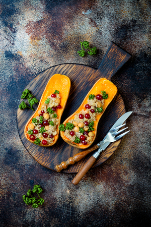 Stuffed butternut squash with chickpeas, cranberries, quinoa cooked in nutmeg, cloves, cinnamon. Thanksgiving dinner recipe. Vegan healthy seasonal fall or autumn foodの写真素材