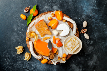 Cheese variety board or platter with cheese assortment, persimmons, honey and nuts.の写真素材