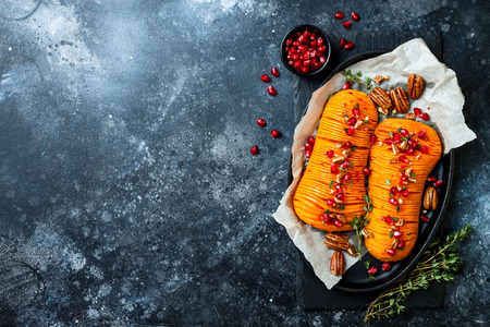Roasted hasselback butternut squash pumpkin with thyme, pecan and pomegranate.の写真素材