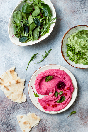 Green pea and pink beet hummus spread or dip with mix salad leaves. Healthy raw summer appetizer, vegan, vegetarian snack.の写真素材