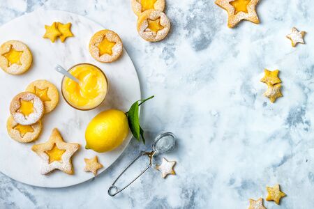 Linzer Christmas cookies filled with lemon curd and dusted with sugar on white marble boardの写真素材