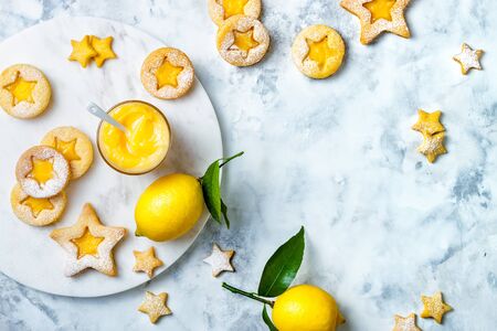 Linzer Christmas cookies filled with lemon curd and dusted with sugar on white marble boardの写真素材