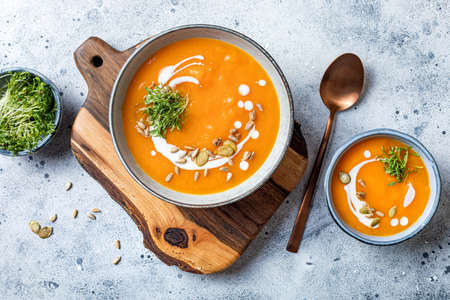 Vegetarian autumn pumpkin and carrot soup with cream, seeds and cilantro micro greens. Comfort food, fall and winter healthy slow food conceptの写真素材
