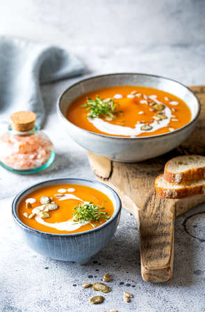 Vegetarian autumn pumpkin and carrot soup with cream, seeds and cilantro micro greens. Comfort food, fall and winter healthy slow food conceptの写真素材