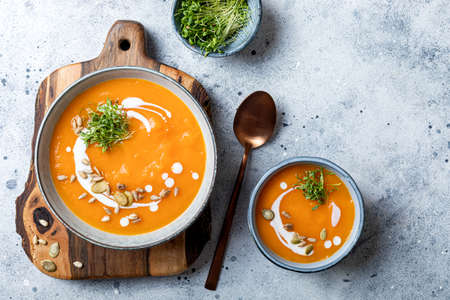 Vegetarian autumn pumpkin and carrot soup with cream, seeds and cilantro micro greens. Comfort food, fall and winter healthy slow food conceptの写真素材