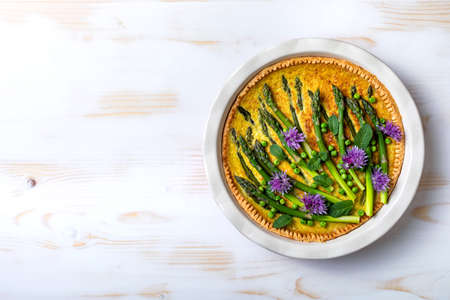Green asparagus, sweet peas Tart with edible chives flowers or blossoms. Seasonal spring dinner,...