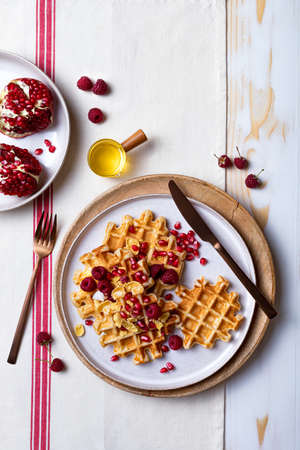 Belgian waffles with honey and raspberries. Breakfast waffles with berry crunch, pomegranate seeds and honeyの写真素材