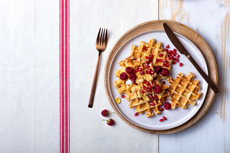 Belgian waffles with honey and raspberries. Breakfast waffles with berry crunch, pomegranate seeds and honeyの写真素材