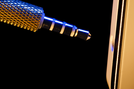 audio jack is connected to a mobile phone isolated on a black background executed in macro techniqueの写真素材
