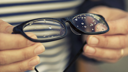 Glasses with rain drops in the girl's hands