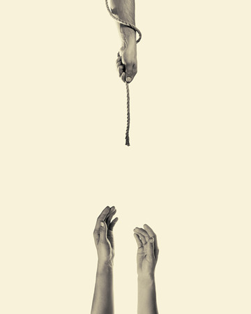 Male hand hands a rope women in distress on toned background, isolatedの写真素材