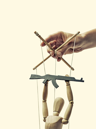 A puppet with  gun in the hands of the tyrant on the isolated toned backgroundの写真素材