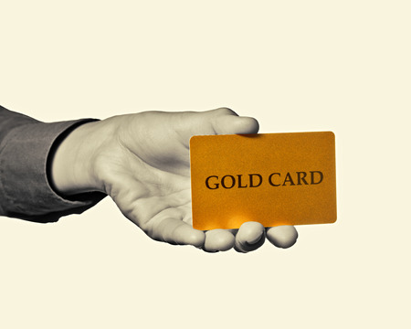 Black and white toned photo a hand with  gold card  on a isolated background