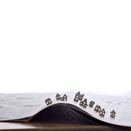 Image of an open newspaper with paper houses. That could mean rent, search, purchase real estate. The template has lot of space for your text.の写真素材