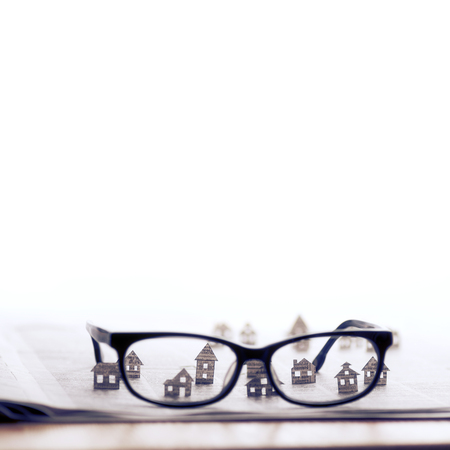 Eyeglasses lie on the open newspaper with paper houses. That could mean rent, search, purchase real estate. The template has lot of space for your text.の写真素材